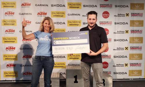 © Fotograf / Peter Perstl / Britta Schwarz von DEBRA Austria und Gregor Lindpointner vom MTB Club Salzkammergut bei der Spendenübergabe nach der Salzkammergut-Trophy 2025. Soziales Engagement seit vielen Jahren: Salzkammergut-Trophy unterstützt wieder die „Schmetterlingskinder“!