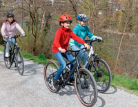 © SPORTaktiv / Thomas Polzer / Spaß am Biken als wichtigstes Argument. Alexander (10, am woom EXPLORE e) und Stella (12) testeten beide für uns das Rad, hier am Grazer Murradweg unterwegs mit ihrer Mutter Verena. E-Bike statt Elterntaxi: Das können Kinder-E-Bikes